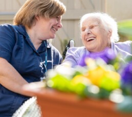 A resident and carer in the garden enjoying a laugh at our Lincoln Care Home